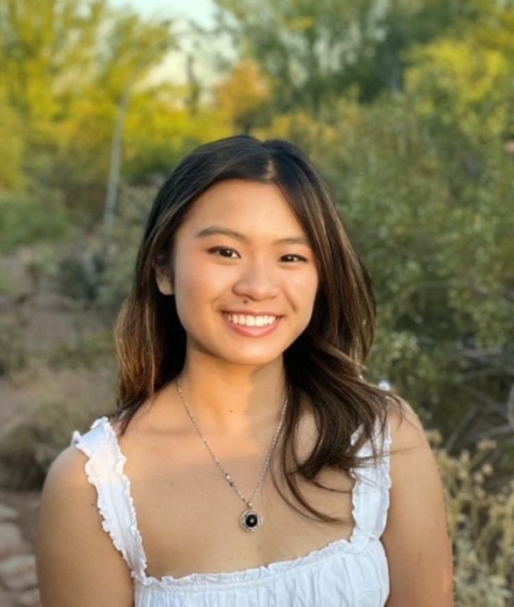 a young woman with curly dark brown hair wearing a white top