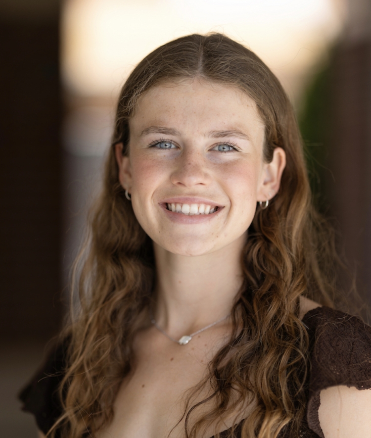 Smiling young woman with curly hair and brown shirt