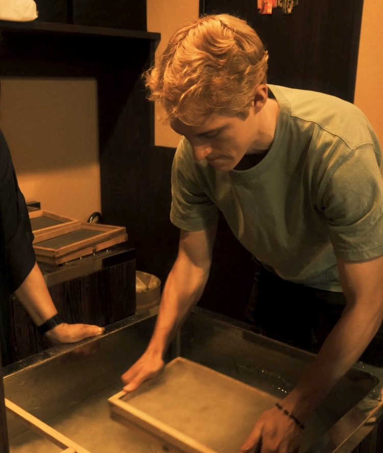 A blonde man making paper by hand