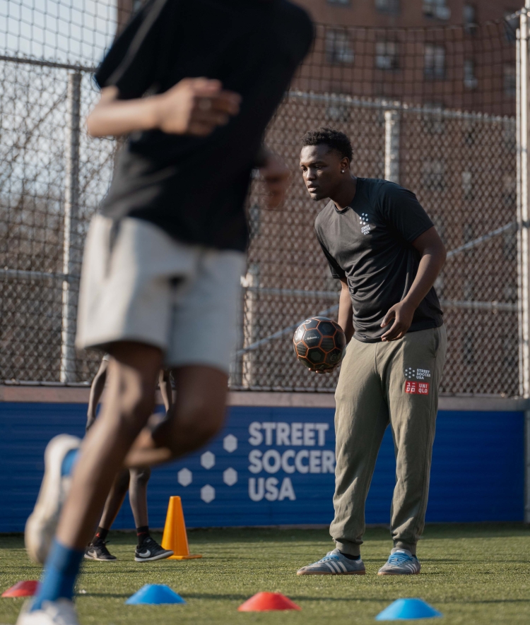 Two young men in athletic gear run obstacles on the soccer field