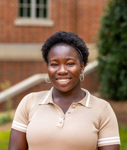 student smiling at camera wearing a beige polo