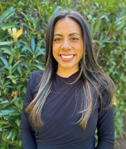 a young woman with brown hair wearing a black top and smiling