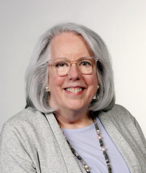 a middle aged white woman with white hair smiling