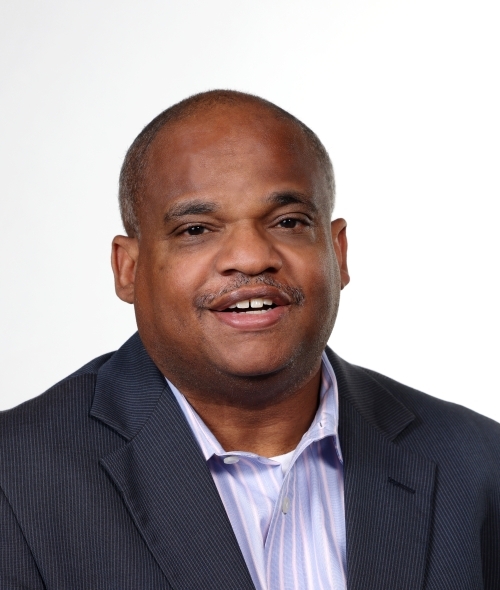 a young Black man wearing a collar and shirt smiling