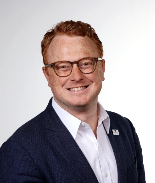 a young white man with red hair wearing glasses