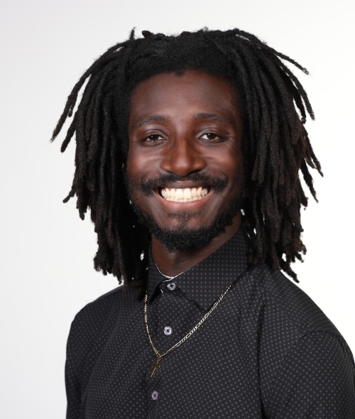a young Black man smiling while wearing a black shirt