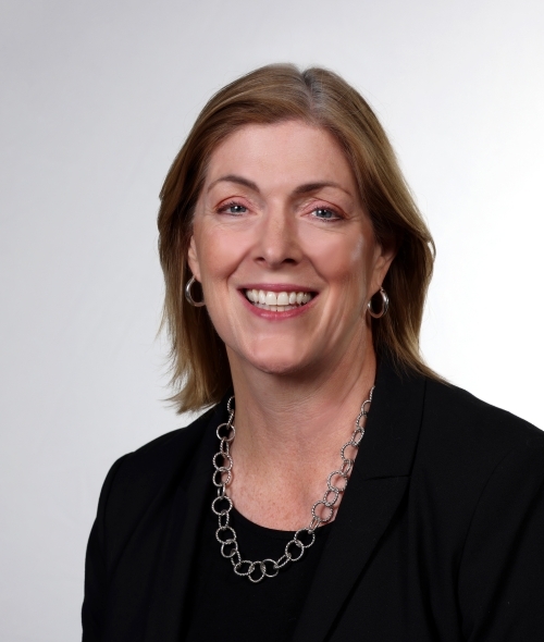 a middle aged white woman wearing black and smiling on a white background