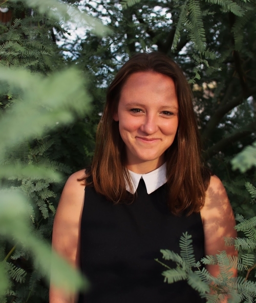 a young white woman wearing a black top with a white collar and smiling