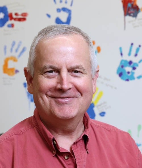 Malcolm Campbell Herman Brown Professor of Biology in front of handprint wall