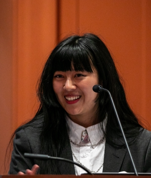 a young Asian woman speaking at a podium and smiling
