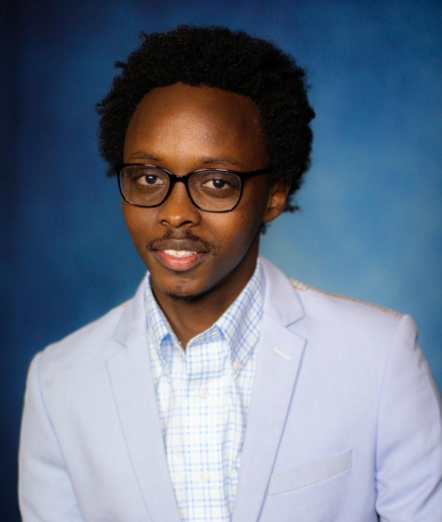 a young Black man wearing glasses and a jacket