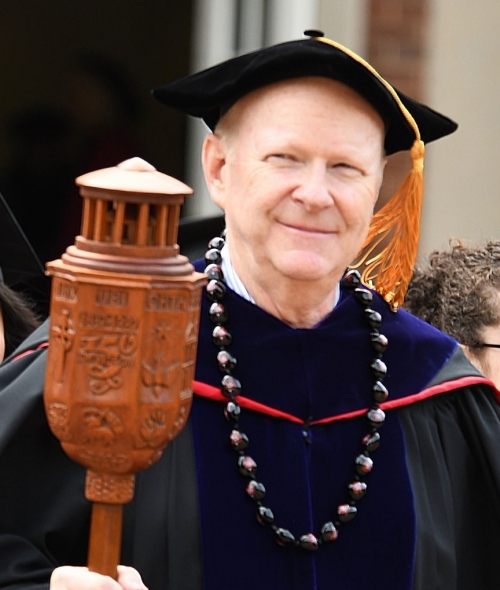 Dan Boye holding academic mace made of ornate carved wood