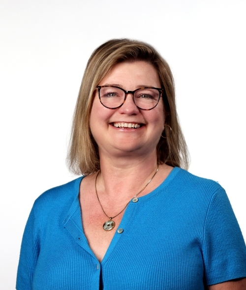 a middle aged white woman wearing glasses and a blue top