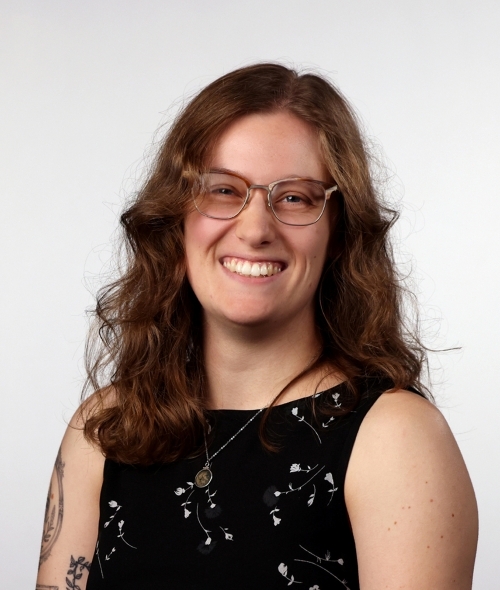 a young white woman with curly brown hair and glasses