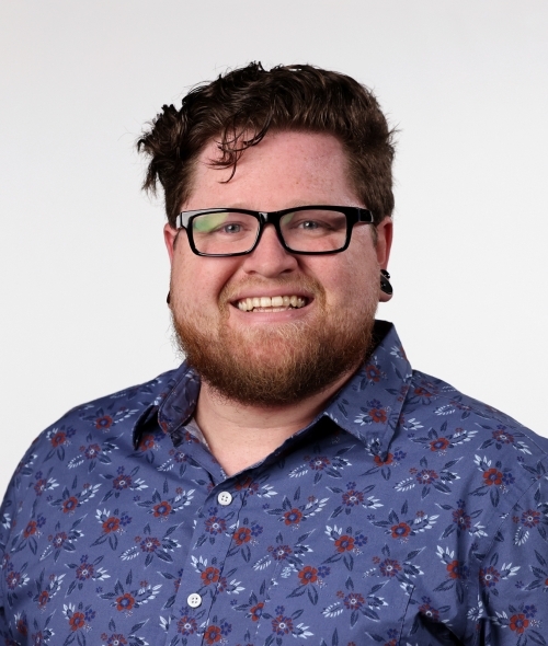 a young white man with glasses and a colorful collared shirt