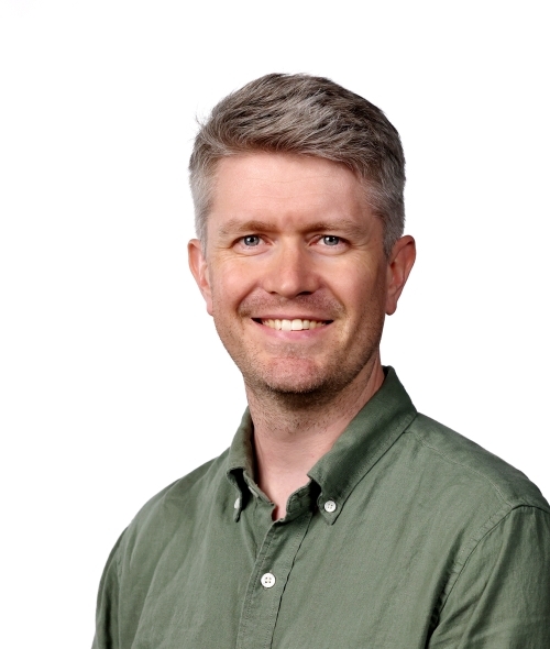 a middle aged white man wearing a green collared top