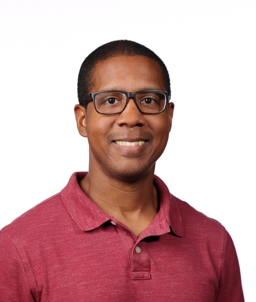 a middle aged Black man wearing glasses and a red collared top