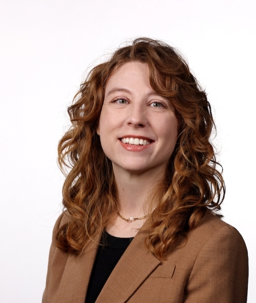 a young white woman with red hair wearing a brown blazer