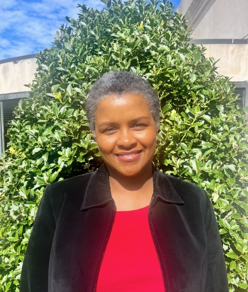 a middle aged Black woman wearing a red top and black jacket