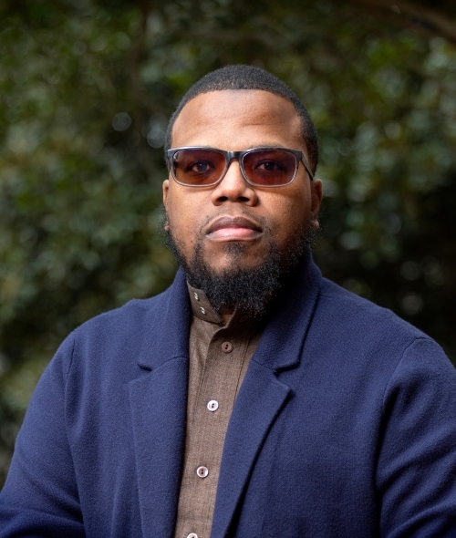 a young Black man wearing a collared shirt and blazer