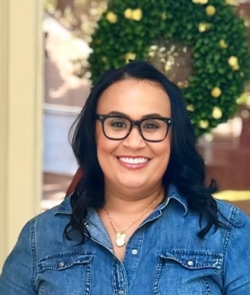 a woman wearing black glasses with dark hair and denim shirt