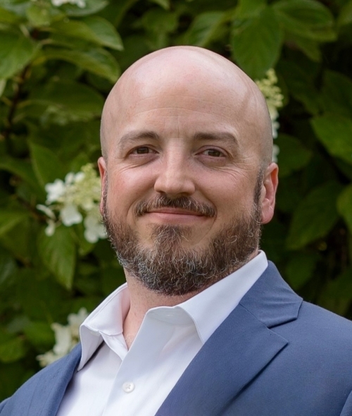 Bald white man with facial hair, a blue blazer and a white button down