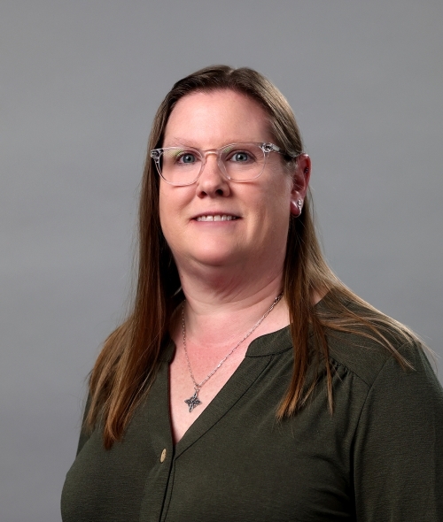 Amy Morand wearing glasses and a grey blouse