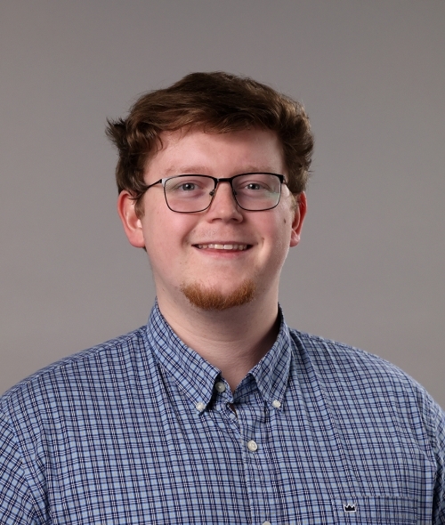 a young white man with reddish hair wearing glasses and a blue collared shirt