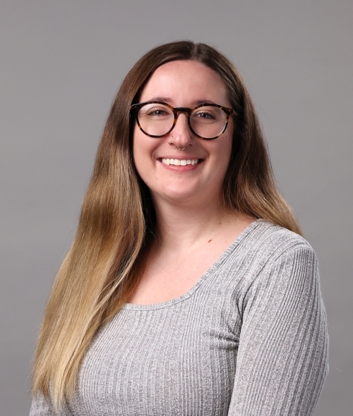 a young white woman wearing glasses and a grey top