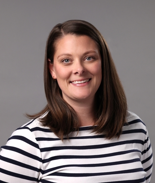 A woman with shoulder-length brown hair wearing a striped shirt