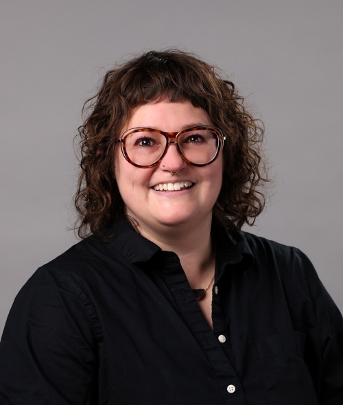 a young white woman with curly brown hair wearing a black buttoned top
