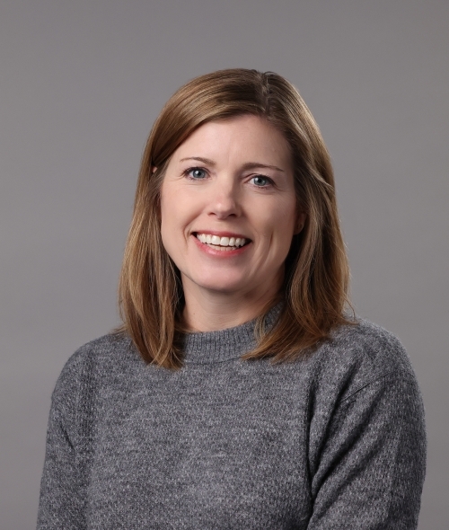 a middle aged white woman wearing a grey sweater