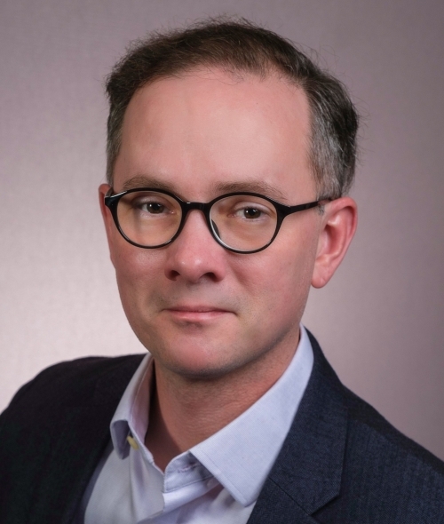 a middle aged white man wearing a shirt and jacket with glasses