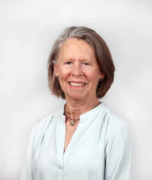 an older white woman with brown hair wearing a white top