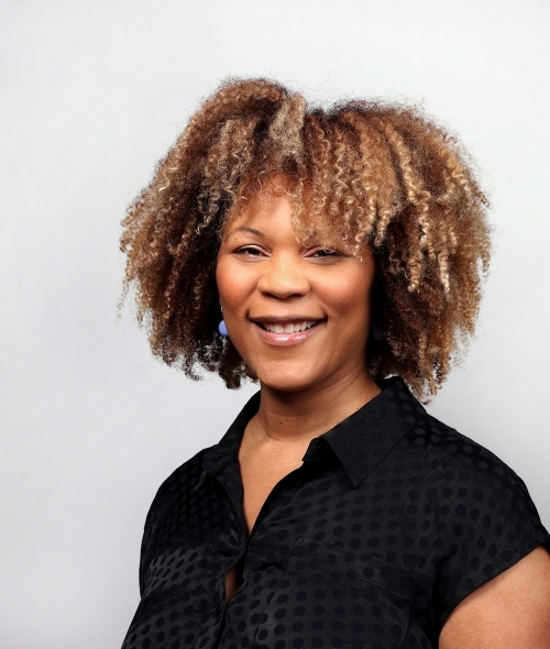 a young Black woman with curly hair wearing a black top
