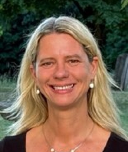 a woman with blonde hair wearing a black top and smiling outside