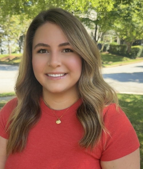 a woman with short brown curly hair wearing a red top