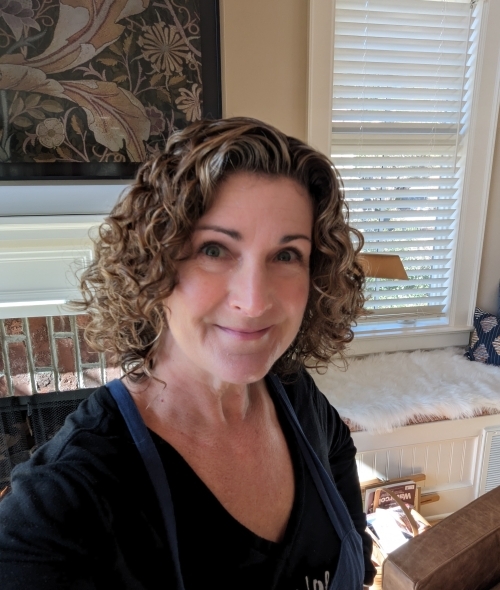 a woman with short curly hair wearing a black tshirt and smiling