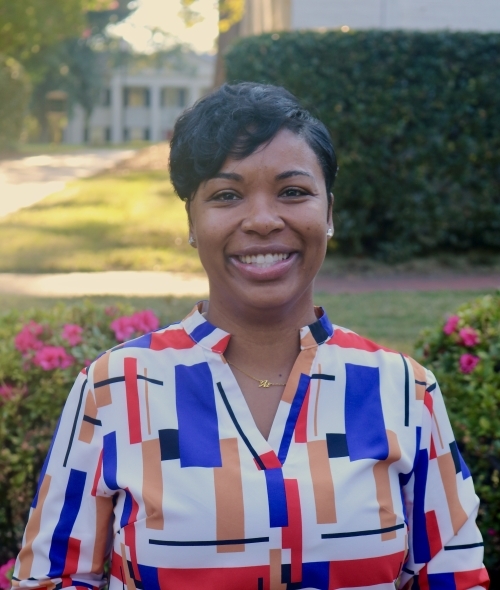 a Black woman with short dark hair wearing a blue, white and red top