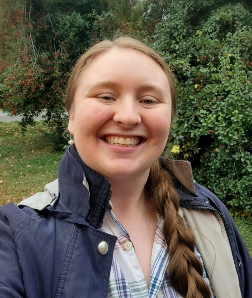 a young woman with a long brown braid wearing a plaid shirt and rain jacket