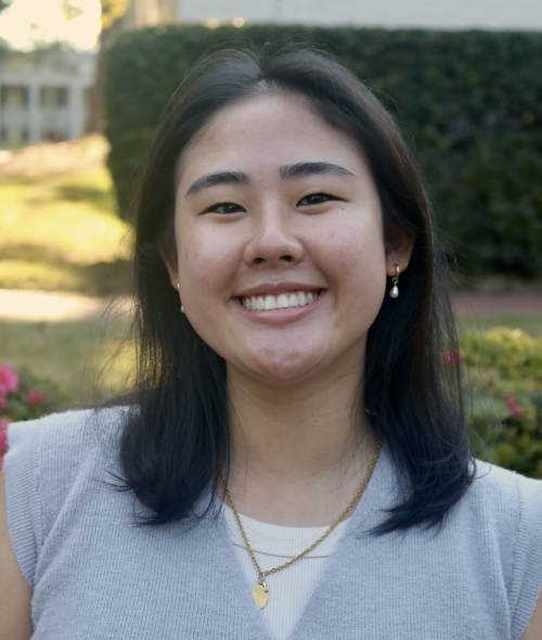 a young woman wearing a sweater vest with short dark hair