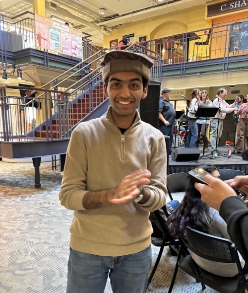 a young man wearing a sweater and jeans and smiling in a college building