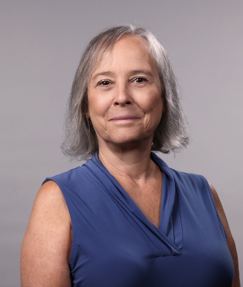 Woman with straight shoulder-length platinum hair and a blue blouse smiles softly