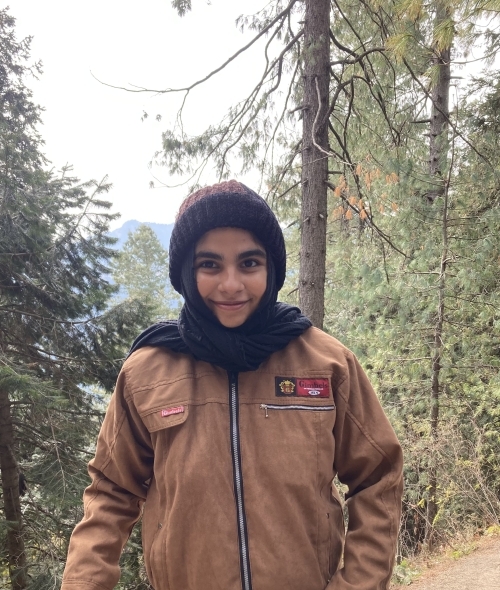 a young woman wearing a beanie and coat while hiking 