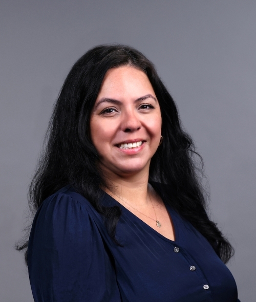 Adult woman smiling with dark brown wavy hair and a navy button-down top