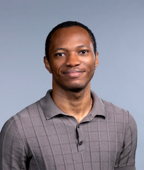 Young man with short black hair wearing a grey polo shirt