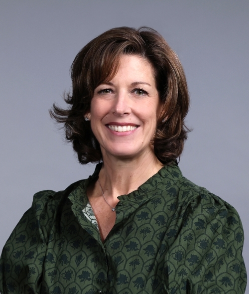A woman with shoulder length brown hair and a green blouse