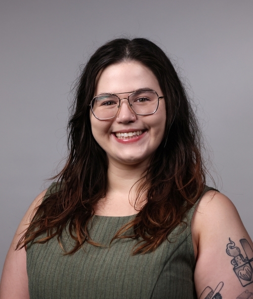 a professor with long dark hair wearing a green top and glasses