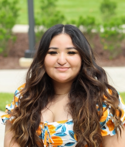 Headshot of young brunette woman with long hair and pleasant smile