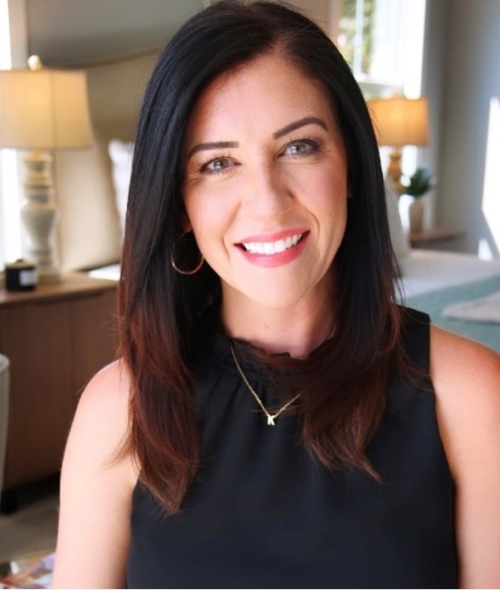 Young adult woman with fair skin, dark brown hair, and a black sleeveless blouse in an office setting